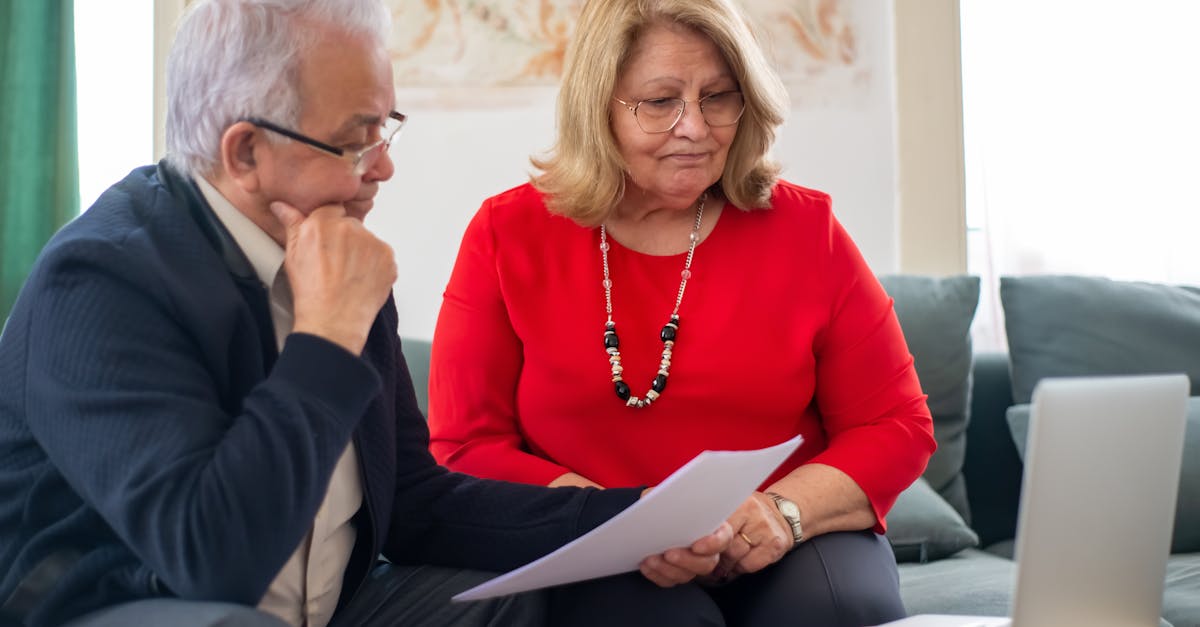 Senior couple examining retirement account statements and mortgage documents at kitchen table