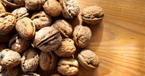Fresh pecans in shell arranged on wooden surface representing heart health benefits